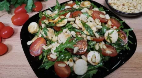 Салат з руколою, помідорами чері, моцарелою та кедровими горішками.